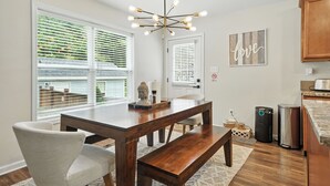 Une cuisine moderne avec une table à manger en bois, un banc et un lustre original.