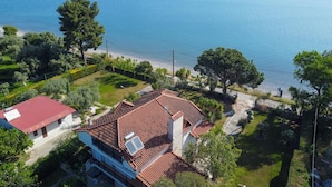 Une propriété située sur la côte, avec un toit recouvert de tuiles rouges, un jardin et une vue sur la mer.