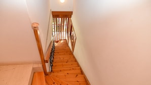 Un escalier en bois avec une rampe et un luminaire au-dessus.