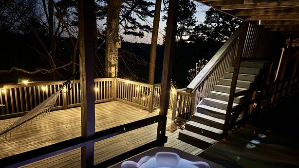 A hot tub with a wooden deck and stairs leading to a covered area.