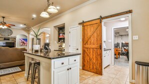 A kitchen with a large island, white cabinets, and a sliding barn-style door. - POOL, Firepit, Gameroom, Great for Families (Lubbock)