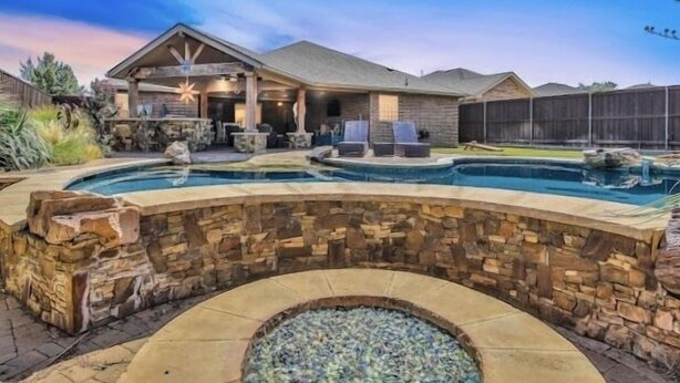 A backyard with a stone pool, a covered patio area, and a stone wall. - POOL, Firepit, Gameroom, Great for Families (Lubbock)