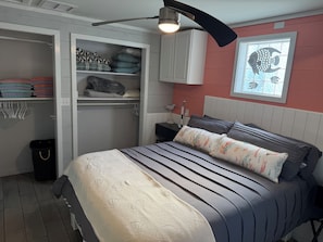 A bedroom with a bed, a nightstand, a lamp, a closet, and a wall-mounted fish decoration.