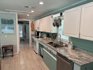 A kitchen with white cabinets, a marble countertop, and a dishwasher.