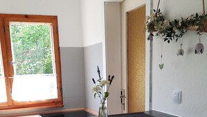 A modern kitchen with a central island, bar stools, a window with a view of greenery, and a decorative plant hanging on the wall. - Idyllic vacation home on Gorinsee / Wandlitz, 45 min. from the center of Berlin (Wandlitz)