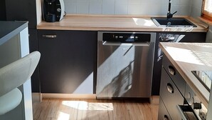 A modern kitchen with dark cabinets, a dishwasher, and a wooden countertop. - Idyllic vacation home on Gorinsee / Wandlitz, 45 min. from the center of Berlin (Wandlitz)