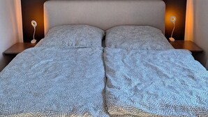 A bed with a patterned blanket, two bedside lamps, and a dark headboard. - Idyllic vacation home on Gorinsee / Wandlitz, 45 min. from the center of Berlin (Wandlitz)
