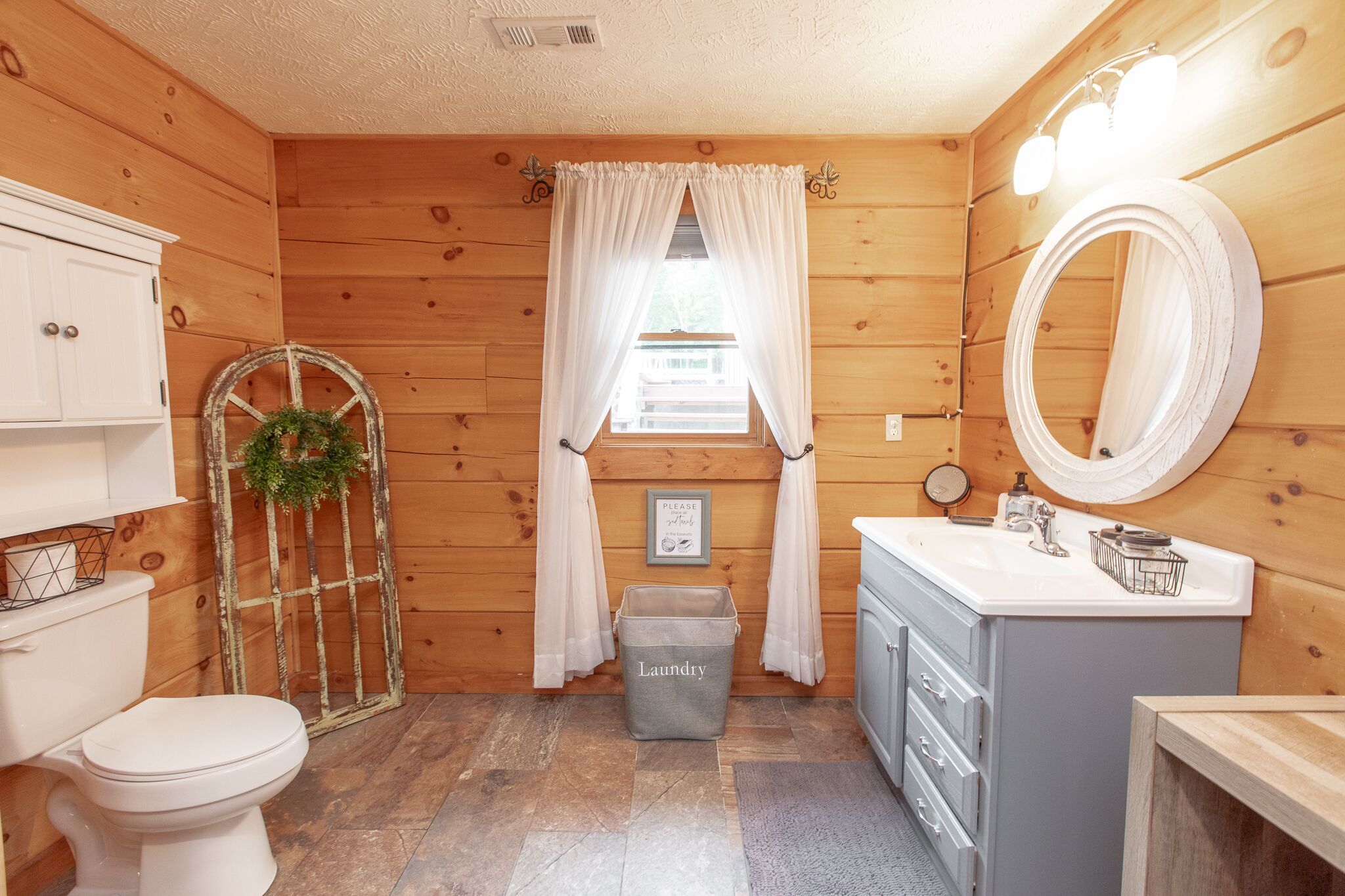 Un baño con paneles de madera, un inodoro, un lavabo y un espejo.