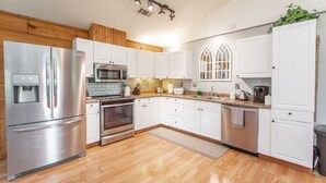 Una cocina moderna con armarios blancos, electrodomésticos de acero inoxidable y piso de madera.