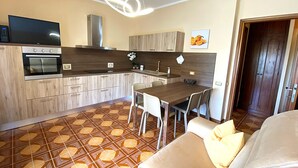 Eine moderne Küche mit Einbauofen, großem Fernseher und Essbereich mit Tisch und Stühlen.