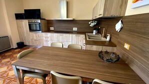 Eine kompakte Küche mit Essecke, Einbauofen und Fernseher.