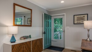 A hallway with a wooden cabinet, a teal door, and a framed picture on the wall. - Lake Escape - Hot Tub & Lake Access - Pet Friendly (Hendersonville)