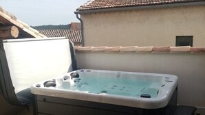 Un bain à remous sur une terrasse, avec une table et des chaises.