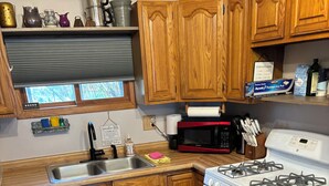 Une cuisine avec des meubles en bois, un évier en acier inoxydable, un four à micro-ondes, une cuisinière à gaz et une machine à café.