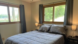 Une chambre à coucher avec un grand lit, deux lampes de chevet, une table de chevet et une fenêtre avec des rideaux.