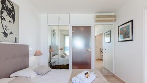 A hotel room with a bed, a mirror, a door, and a wall with a framed picture. - Waterfront - splendid apartment (Cannes)