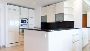 A modern kitchen with white cabinetry, a black countertop, and built-in appliances. - Waterfront - splendid apartment (Cannes)