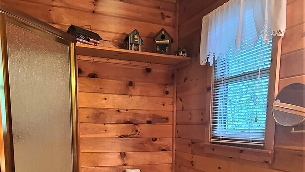 Une salle de bain rustique, aménagée dans une cabane en bois, avec des toilettes, un lavabo et une fenêtre.
