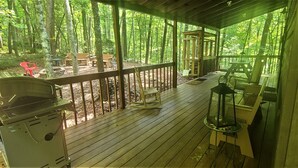 Eine überdachte Terrasse im Freien mit Grill, Sitzgelegenheit und Laterne.