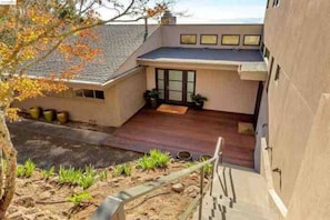 A modern building with a flat roof, a covered patio area, and a small garden with plants and a pathway. - Berkeley Hills: Stunning Views & Luxury Home, Fab Location, Hiking Trails & City (Berkeley)