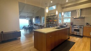 Una cocina moderna con armarios de madera, una isla grande, electrodomésticos de acero inoxidable y una zona de comedor con mesa y sillas.