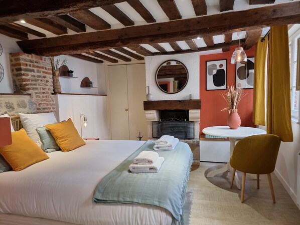 Une chambre à coucher comprenant un lit, un bureau, une chaise, une cheminée et un miroir.