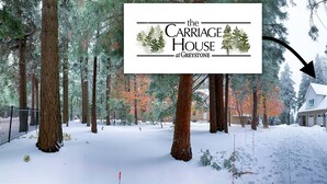 Ein verschneiter Waldweg führt zu einem Haus mit dem Schild 'The Carriage House at Greystone'.