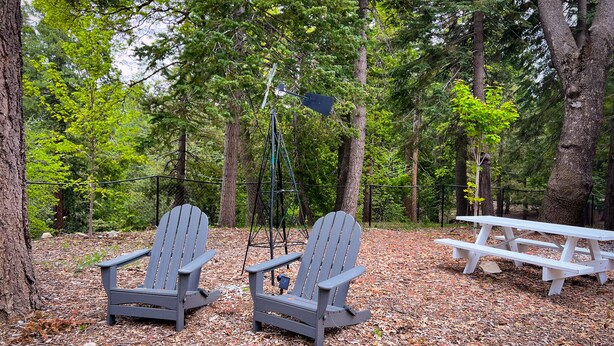 Un área boscosa con dos sillas Adirondack y una mesa de picnic.