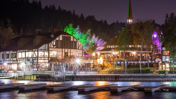 Ein Hotel am Wasserufer mit einem großen Speisesaal, einer Kirche mit Kirchturm und einer Brücke.