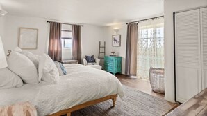 Une chambre à coucher avec un grand lit, une commode, une chaise et une fenêtre avec des rideaux.