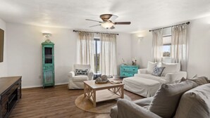 Un salon spacieux doté d’un ventilateur de plafond, d’une table basse en bois et d’un meuble turquoise.