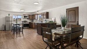Une cuisine moderne avec des meubles en bois, un îlot central et un coin repas comprenant une table et des chaises en bois.