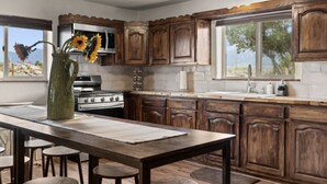 Une cuisine avec des meubles en bois, un îlot central, une cuisinière et une grande fenêtre.