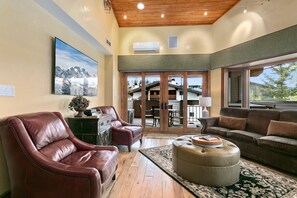 A spacious living room with leather furniture, a large painting, and a view of the outside. - Royal Plaza at Deer Valley - One Bedroom Condo with Hot Tub #305 by RedAwning (Park City)