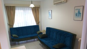 Una sala de estar con un sofá azul, una mesita y un ventilador de techo.