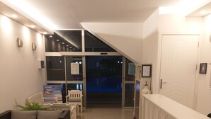 Un hall de hotel con mostrador de recepción, zona de estar y vista a la piscina.