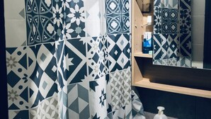 A bathroom with patterned tiles, a sink, a mirror, and a shower curtain. - Entire apartment (Reims)