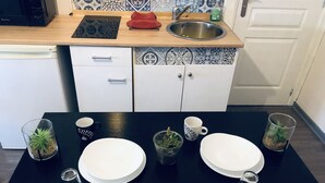 A kitchen with a microwave, sink, and cabinets. There are two white plates, two cups, and a glass on the counter. - Entire apartment (Reims)