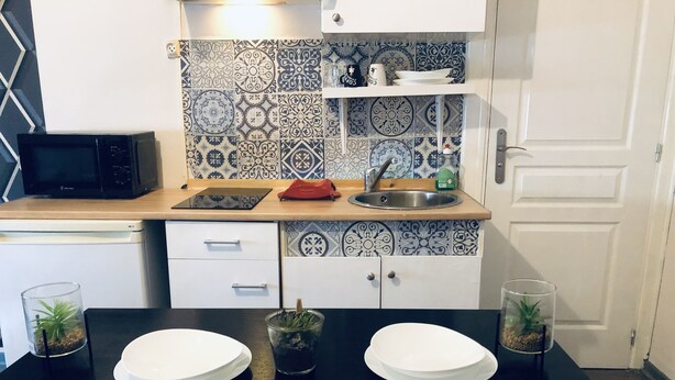 A kitchen with a black countertop, white cabinets, and a patterned backsplash. - Entire apartment (Reims)