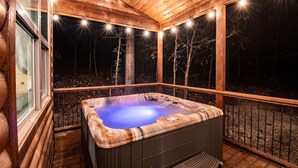 A wooden cabin with a hot tub on a deck, surrounded by trees. - Three Wildflowers Cabin - cozy retreat for up to 6 (Broken Bow)