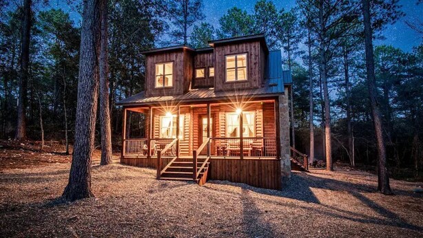 A wooden cabin with a porch and a staircase, surrounded by trees. - Three Wildflowers Cabin - cozy retreat for up to 6 (Broken Bow)