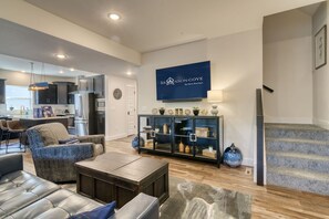 A modern living room with a sofa, coffee table, and a decorative cabinet. - Near State Park Marina with Game Room, Private Hot Tub, Golf Cart, Community Pools & Free Tickets! (Hollister)