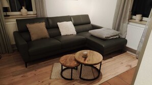 A living room with a dark green sectional sofa, two round wooden coffee tables, and a patterned rug. - Vacation house-Braunlage apartment 2 (Braunlage)