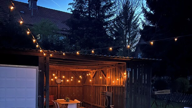 A wooden shed with a table and chairs set up inside, surrounded by a string of lights. - Vacation house-Braunlage apartment 2 (Braunlage)