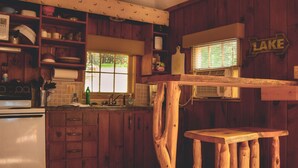 Una cocina rústica con armarios de madera, estufa empotrada y una ventana con persianas.