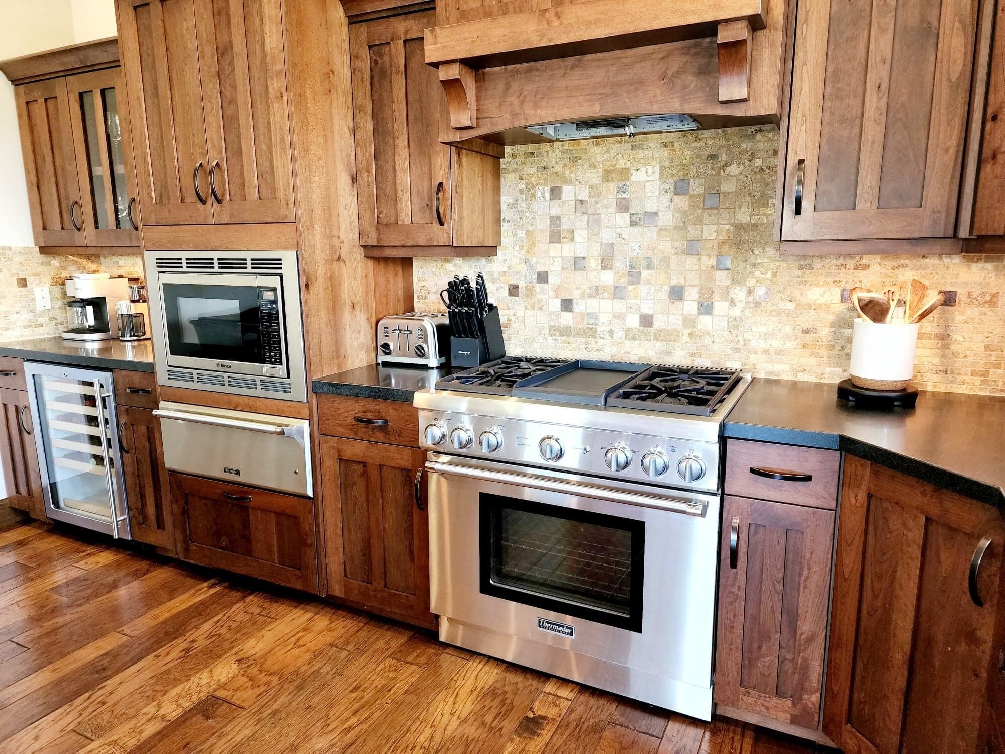A kitchen with wooden cabinets, a Bosch microwave, a toaster, a Thermomaster stove, and a coffee maker.