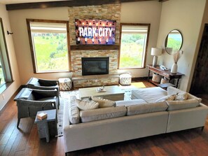 A living room with a stone fireplace, a large TV, and a sofa. - Luxury Deer Valley East Retreat with Stunning Lake Views - 1.5 miles from slopes (Heber City)