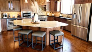 Una cocina moderna con armarios de madera, electrodomésticos de acero inoxidable y una isla central con taburetes de bar.
