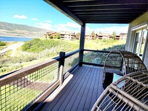 A wooden deck with a view of a lake and buildings in the background.