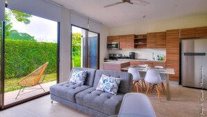 A modern kitchen with wooden cabinets, a stainless steel refrigerator, and a dining area with white chairs. - Captivating 2-bed Apartment (Jacó)